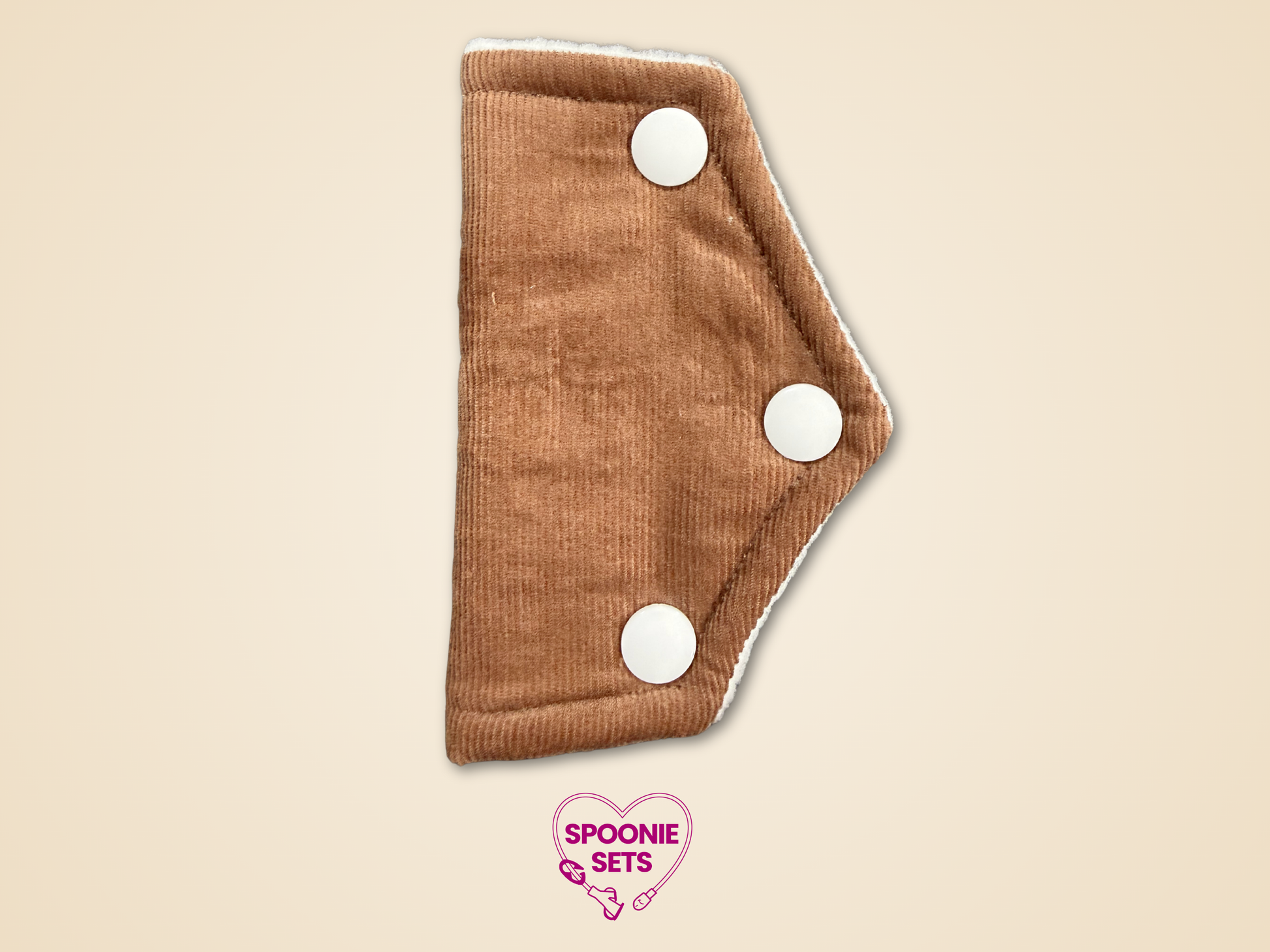 Brown cloth pad with white buttons on a beige background, featuring 'Spoonie Sets' logo.