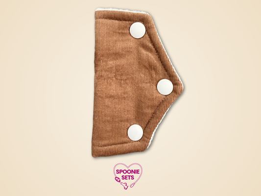 Brown cloth pad with white buttons on a beige background, featuring 'Spoonie Sets' logo.