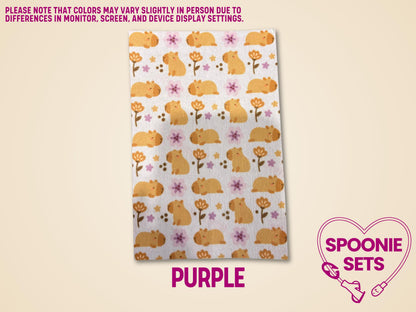 Decorative Hypafix tubie tape sheet with a pattern of orange capybaras and purple and orange flowers.