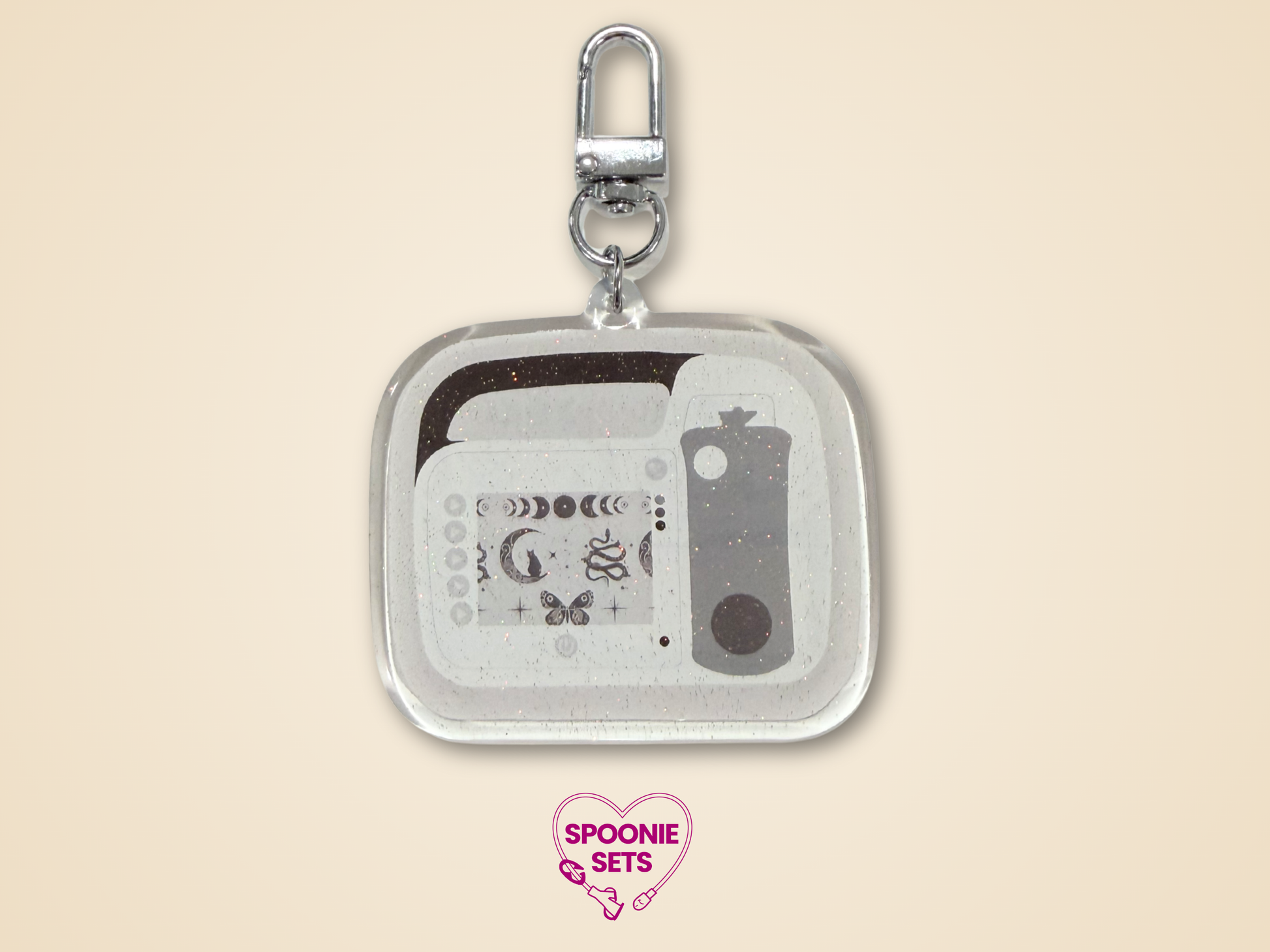 Keychain Side B with white, light gray, and dark gray feeding tube pump design with celestial accents and silver hardware