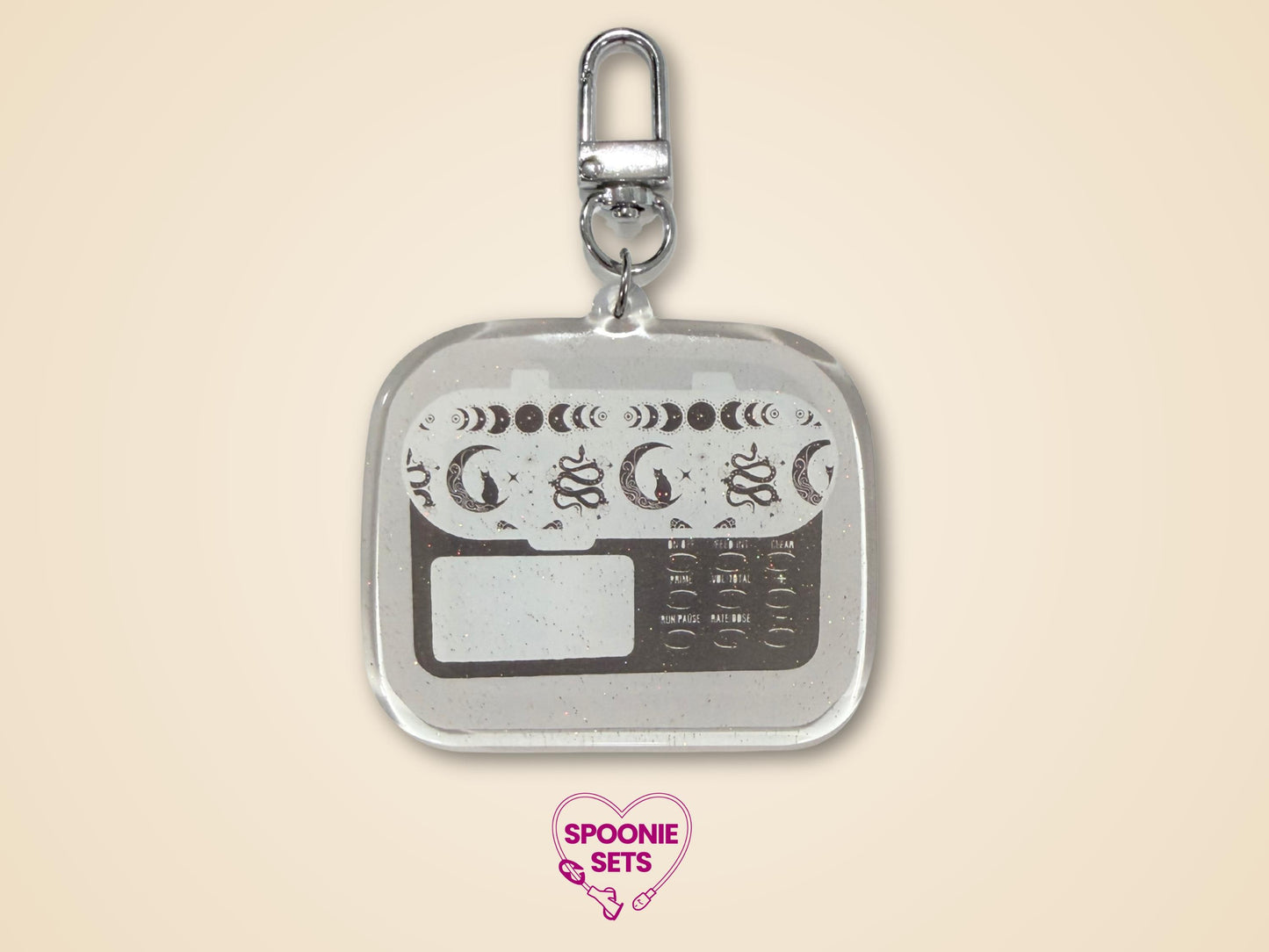 Keychain with white, light gray, and dark gray feeding tube pump design with celestial accents and silver hardware
