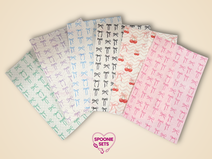 Six sheets of decorative Hypafix tubie tape with pink, purple, blue, black, and green bow patterns.