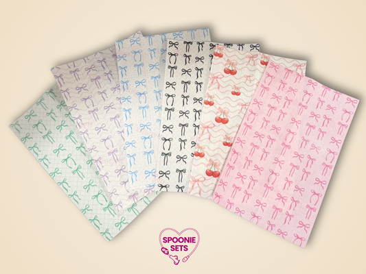 Six sheets of decorative Hypafix tubie tape with pink, purple, blue, black, and green bow patterns.