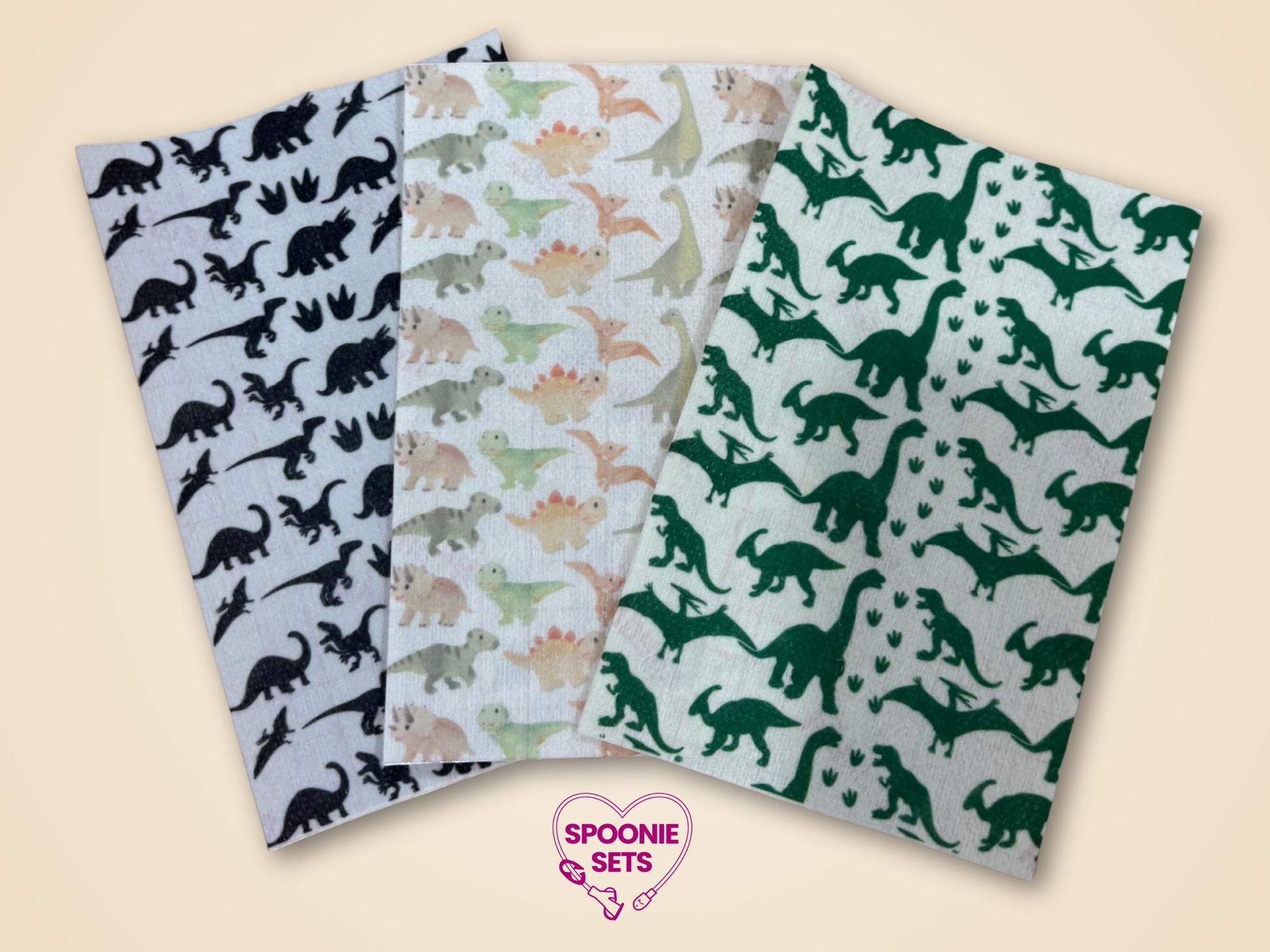 Three sheets of decorative Hypafix tubie tape with dinosaur patterns: black, pastel, and green.