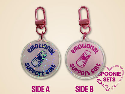 Holographic acrylic keychain with "Emotional Support Salt" text and salt shaker design, featuring pink hardware.