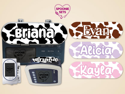 Pink, purple, brown, and black cow print feeding tube pump stickers with personalized names.