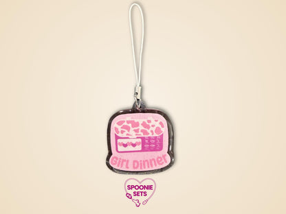 Pink glitter epoxy acrylic phone charm with "Girl Dinner" and a feeding tube pump design.