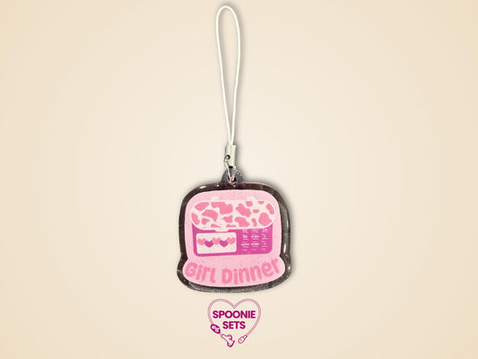 Pink glitter epoxy acrylic phone charm with "Girl Dinner" and a feeding tube pump design.