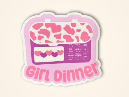 Sticker featuring a feeding tube pump design in pink and purple with the text 'Girl Dinner' in pink, shown on a light cream background.