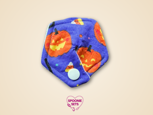 Blue pad with Halloween-themed pumpkins on a beige background, featuring 'Spoonie Sets' logo.