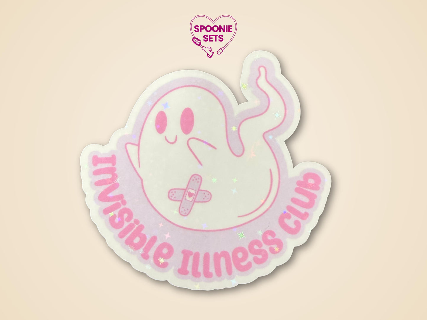 Holographic glitter sticker of a cute ghost with a bandage, text "Invisible Illness Club" in pink.