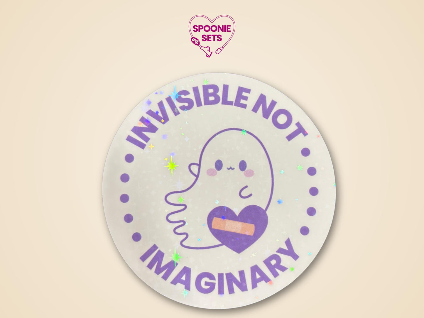 Round holographic glitter sticker with a cute ghost, purple heart with a bandage, and "Invisible Not Imaginary" text.