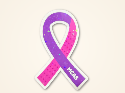 An  awareness ribbon sticker with a purple and pink design with the white text 'MCAS' on the lower loop, shown on a light beige background.
