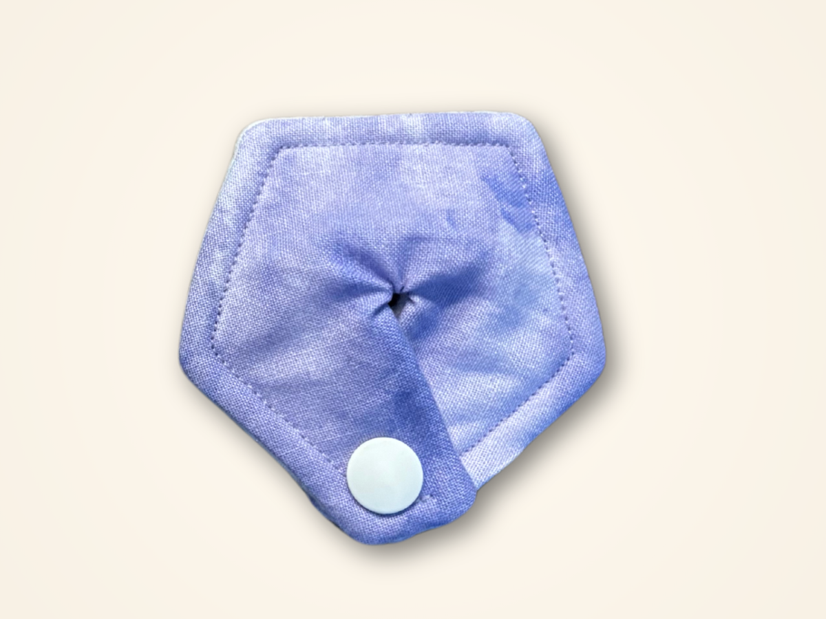 A purple reusable cloth pad with a snap-button closure, shown on a solid cream background.