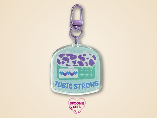 Keychain with 'Tubie Strong'  feeding tube design on a beige background