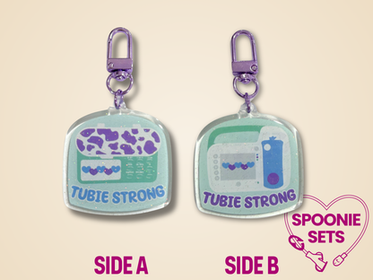 Two 'Tubie Strong' keychains with different feeding tube pump designs on each side.