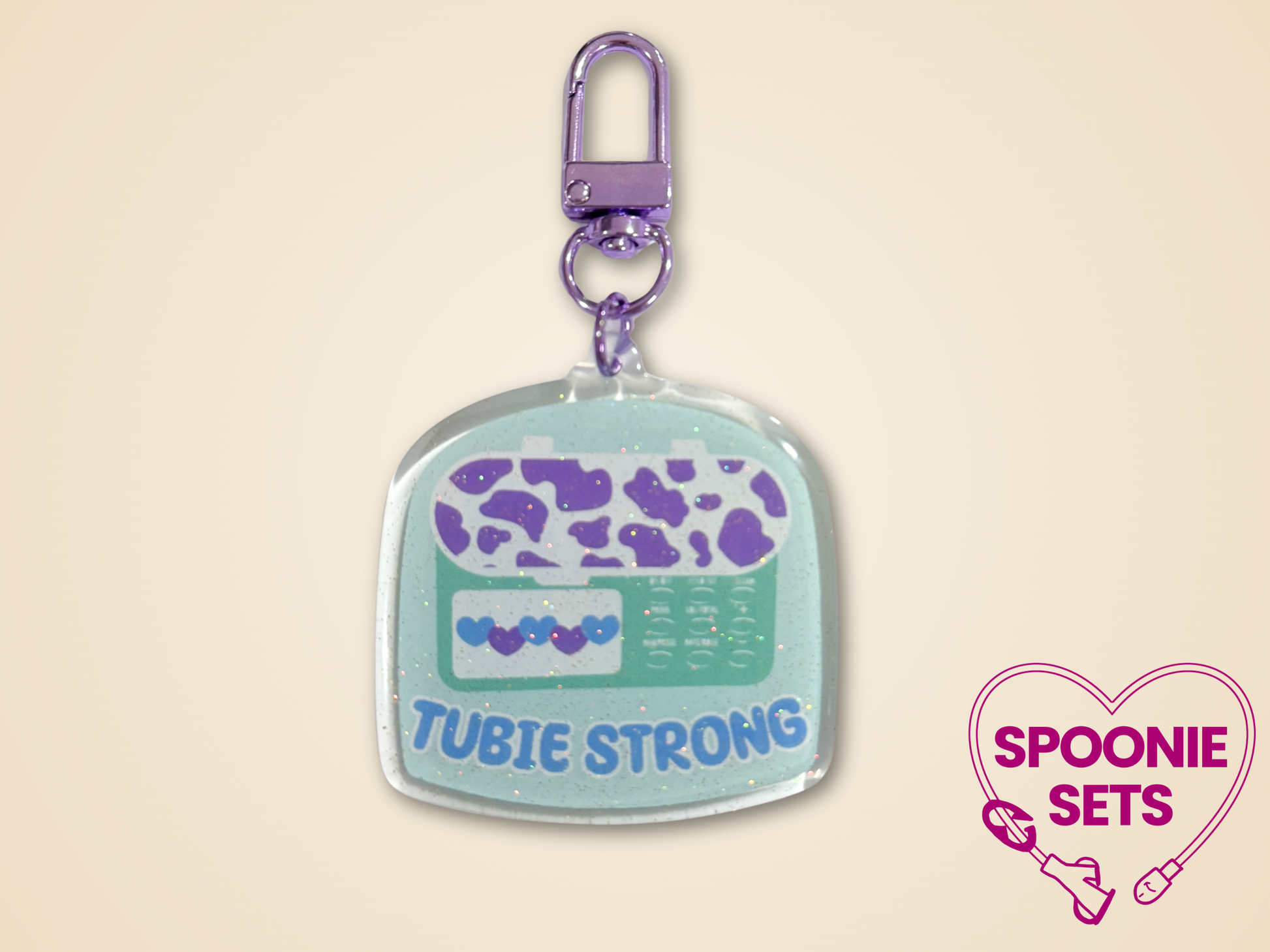 Keychain with purple and teal design  of feeding tube pump and 'Tubie Strong' text.