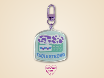 Keychain with 'Tubie Strong'  feeding tube design on a beige background