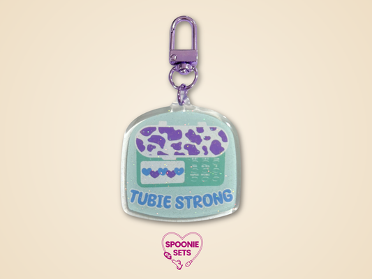 Keychain with 'Tubie Strong'  feeding tube design on a beige background