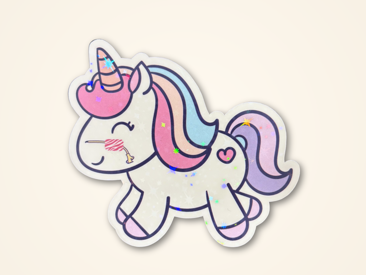 A sticker featuring a cute cartoon unicorn with pastel pink, blue, and purple colors, nasal feeding tube, and a small heart on its side, shown on a light cream background.