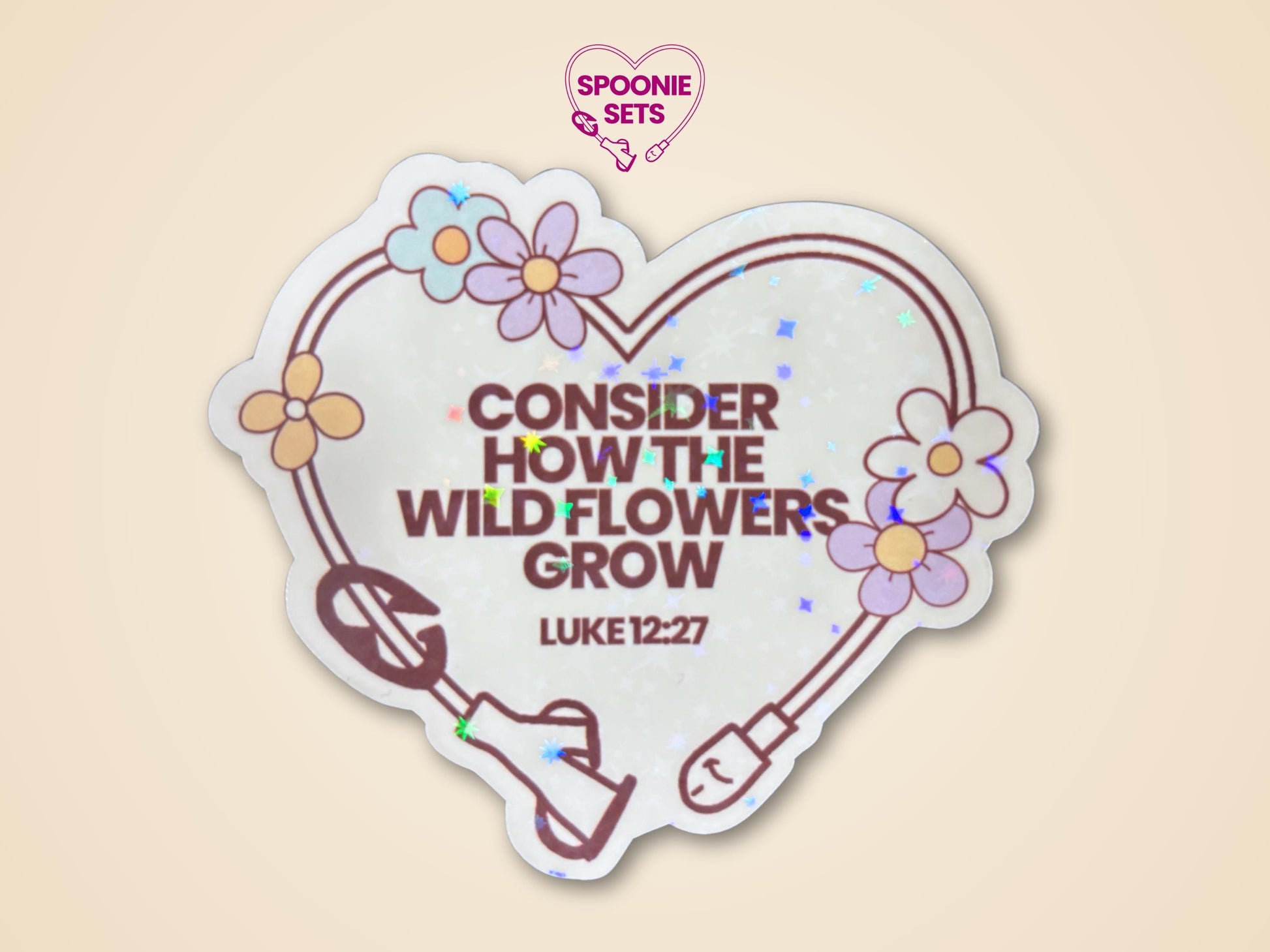 Holographic glitter sticker, 3"x2.6", with a heart-shaped feeding tube, wildflowers, and "CONSIDER HOW THE WILD FLOWERS GROW LUKE 12:27" text.