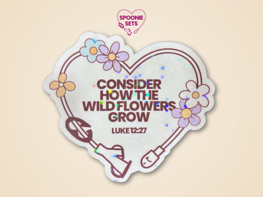 Holographic glitter sticker, 3"x2.6", with a heart-shaped feeding tube, wildflowers, and "CONSIDER HOW THE WILD FLOWERS GROW LUKE 12:27" text.