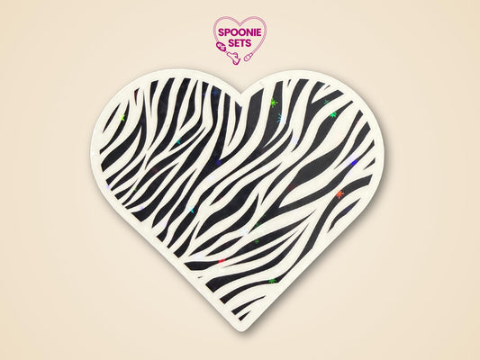 Heart-shaped zebra print sticker with black stripes and subtle holographic glitter, promoting rare disease awareness.